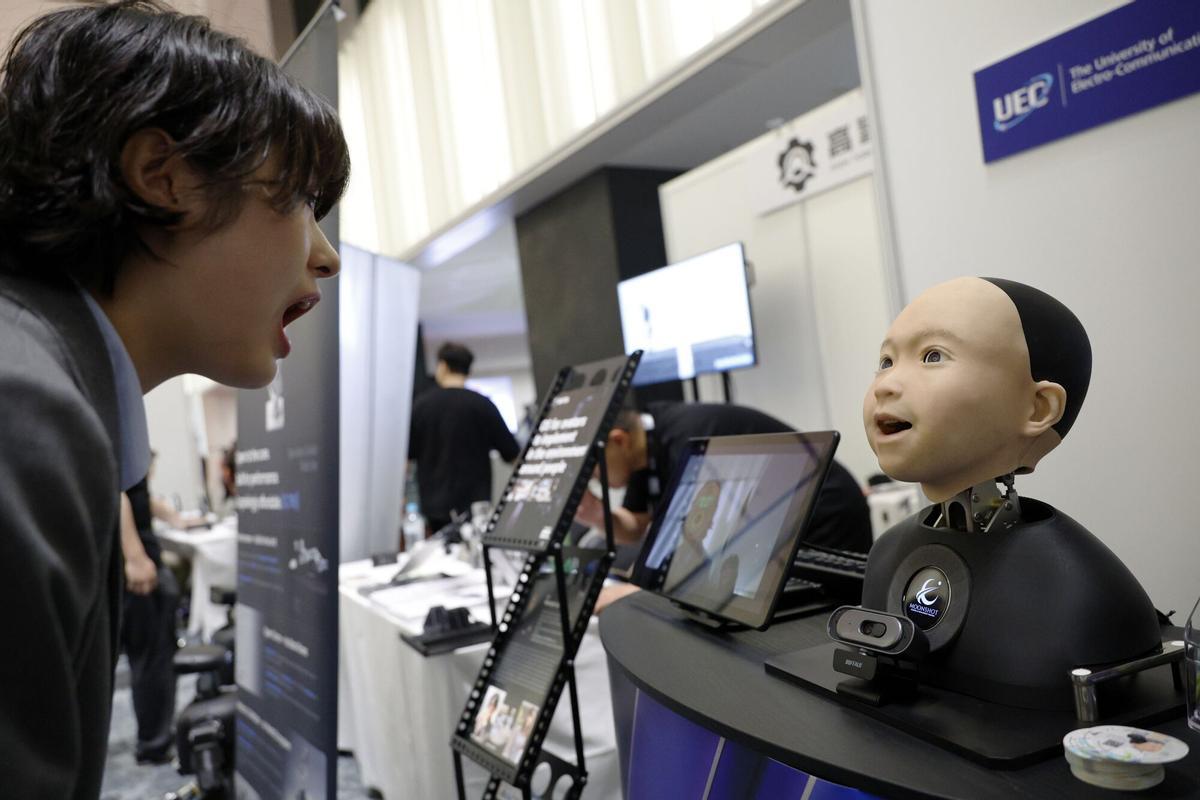 Una joven interactúa con un robot humanoide en el stand de Avita durante la Cumbre de Humanoides en Tokio, Japón