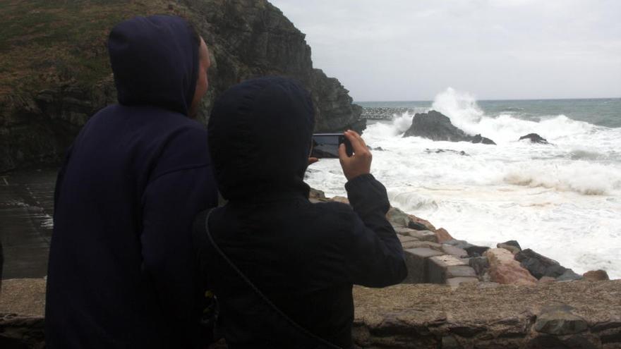 Curiosos que s&#039;acosten a veure les onades picar a la punta de la plata de la Gola, a Llançà.