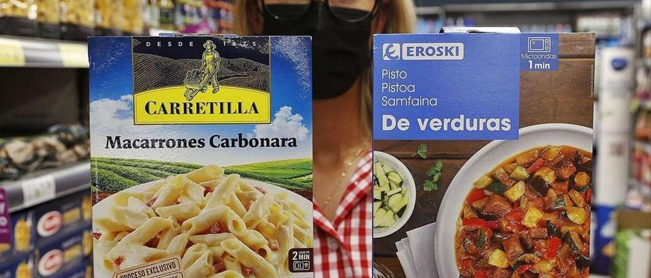 Una empleada de un Eroski muestra dos productos con diferente nota.