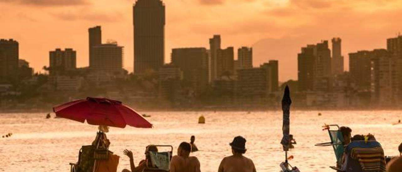 Turistas en la playa de Benidorm, con parte del «skyline» al fondo.