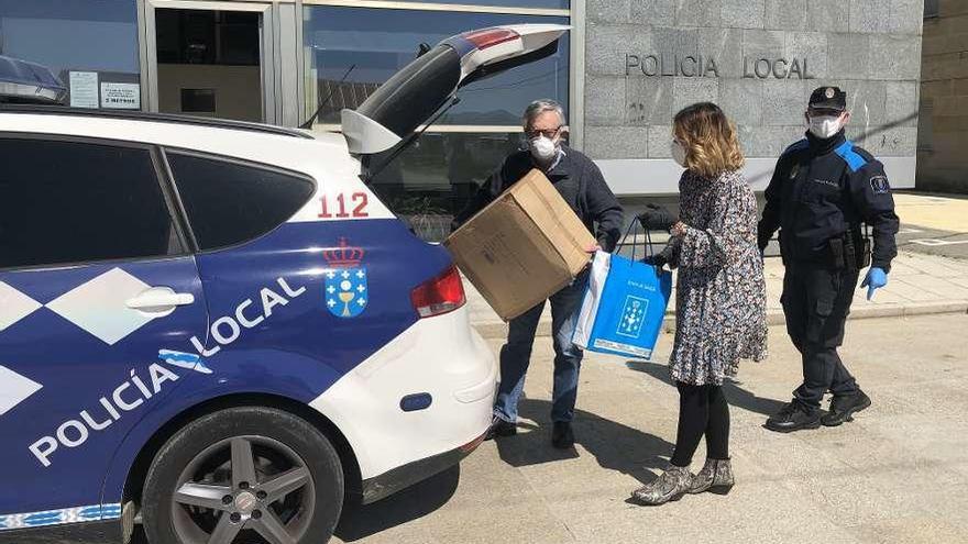 Pazos y Martínez, cargando material en un coche de la Policía con destino a la residencia de Aldán. // G.N.