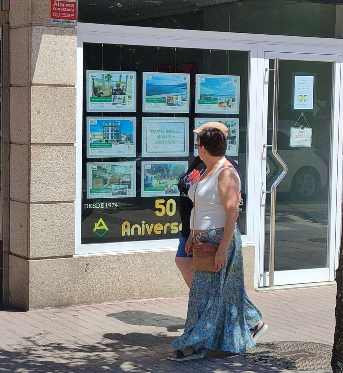 Vecinos, ayer, observando el escaparate de una inmobiliaria en Cangas.