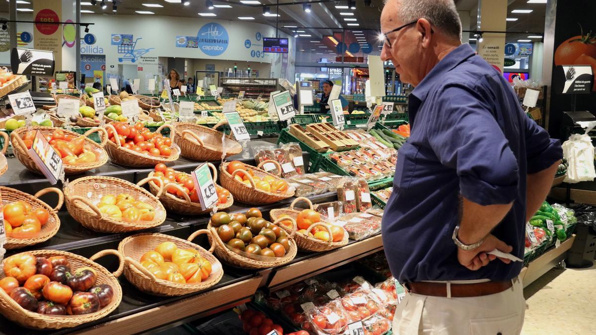 Un home compara preus de verdures en un supermercat