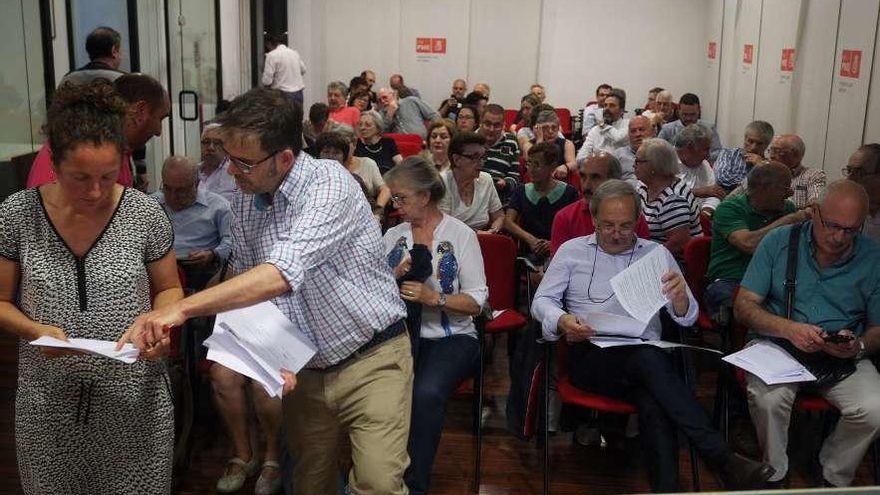 Piñuela, a la izquierda, reparte documentación en la asamblea de la AMSO; en primera fila, el Alcalde.