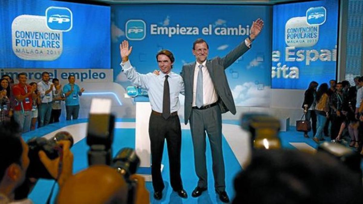 José María Aznar y Mariano Rajoy saludan a los militantes que asistieron ayer a la primera jornada de la convención del PP en Málaga.