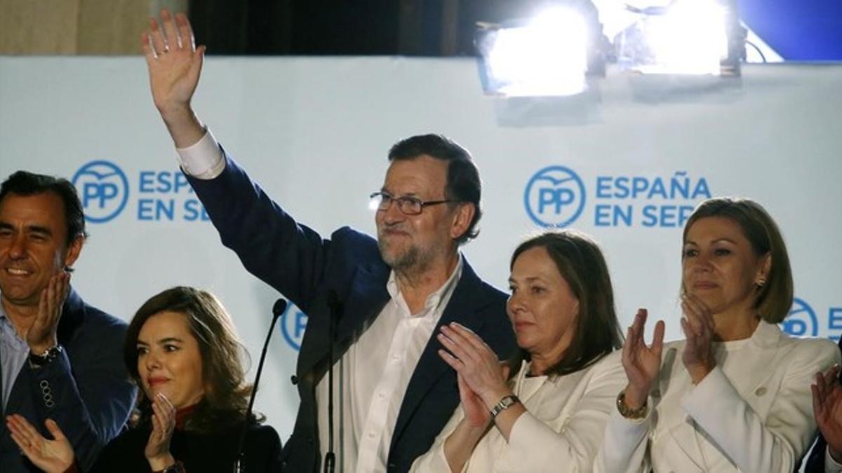Rajoy y junto a compañeros del partido en el balcón de la sede del PP.