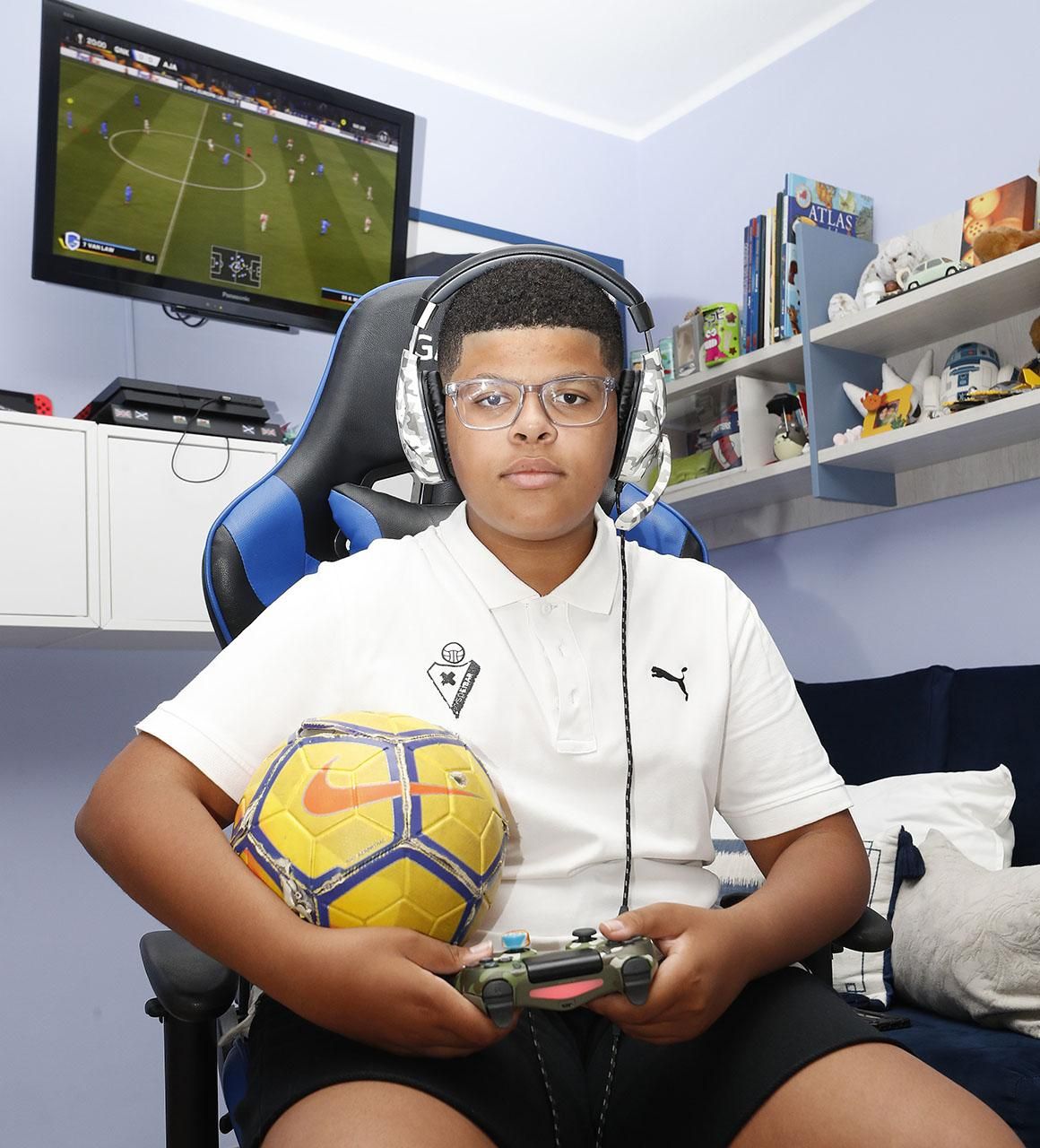 El joven vigués, en su cuarto, con un balón de fútbol y un mando de la PlayStation 4.