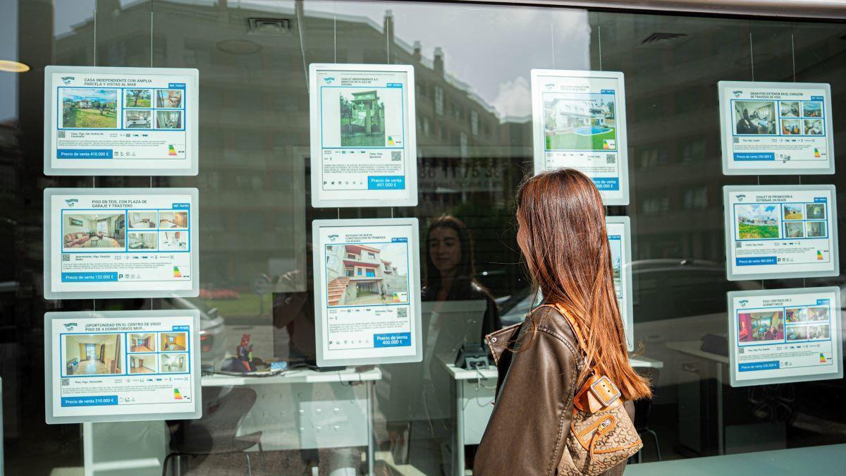 Mujer observa anuncios de alquiler y compra en una inmobiliaria.