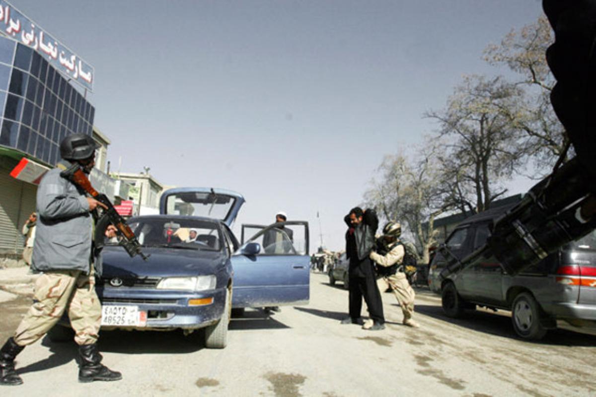 Diversos oficials afganesos registren vehicles i escorcollen els seus ocupants en un punt de control muntat a Ghazni (Afganistan)