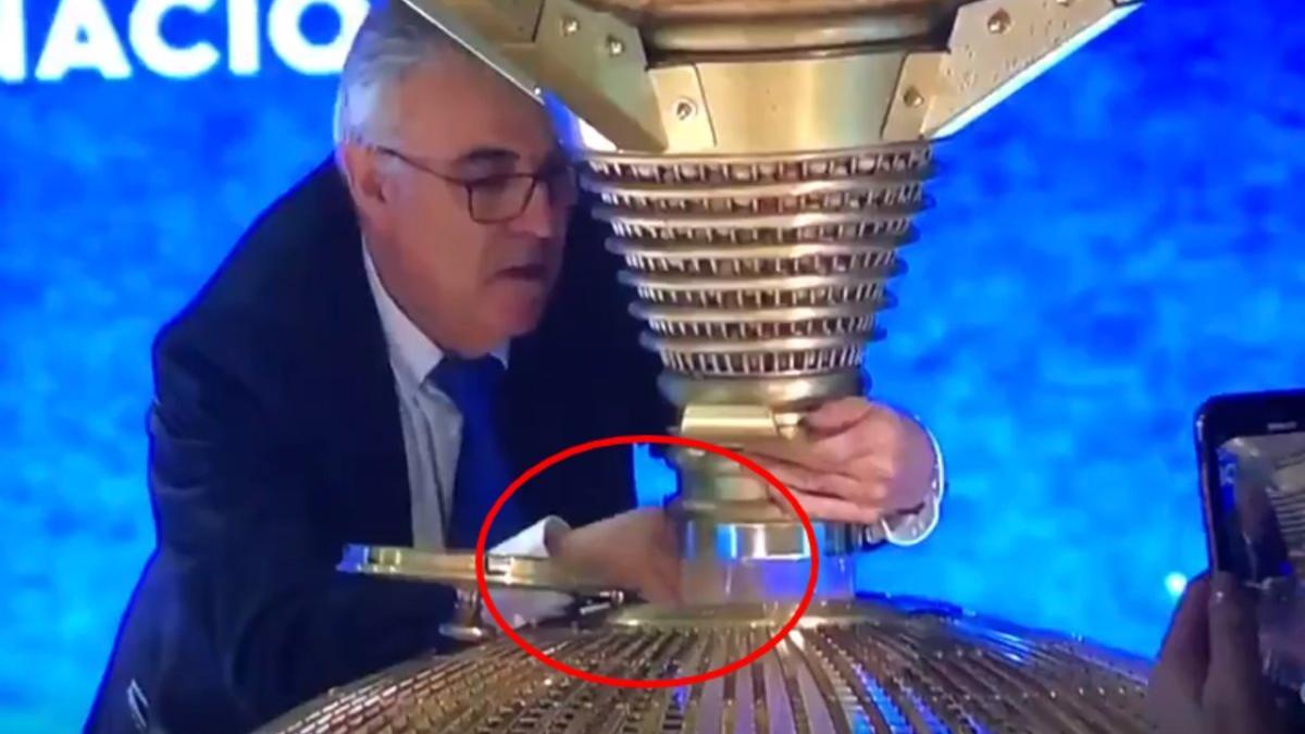 Vídeo en el que se puede ver cómo el el operario de Loterías del Estado, que lleva algo sujeto en su mano derecha, la abre y lo deja caer en el bombo