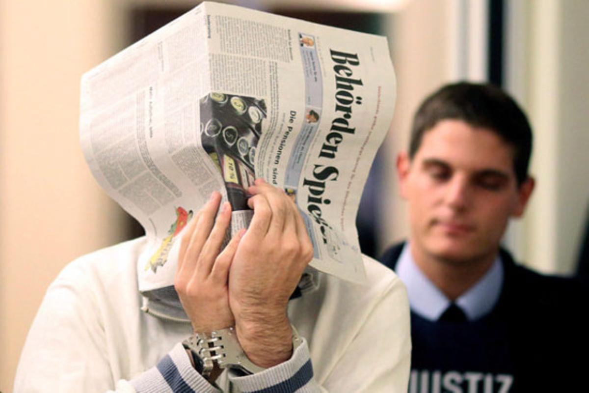 Hussam S., de 25 anys, acusat de recolzar l’organització terrorista Al-Qaida, es tapa la cara amb un diari durant el seu judici al Tribunal Suprem de Koblenz (Alemanya).