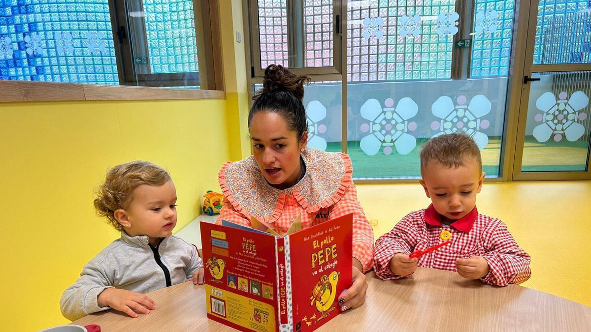 Dos niños, junto a una educadora, en la Escuelina Los Polesinos de Pola de Siero.