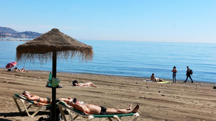 Dos turistas disfrutan del sol en La Malagueta.