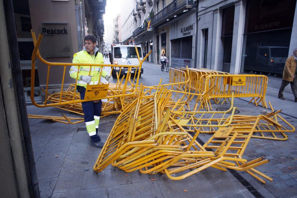 Carrers amb restes de mobiliari urbà cremat, contenidors per terra i treballadors de la brigada treballant