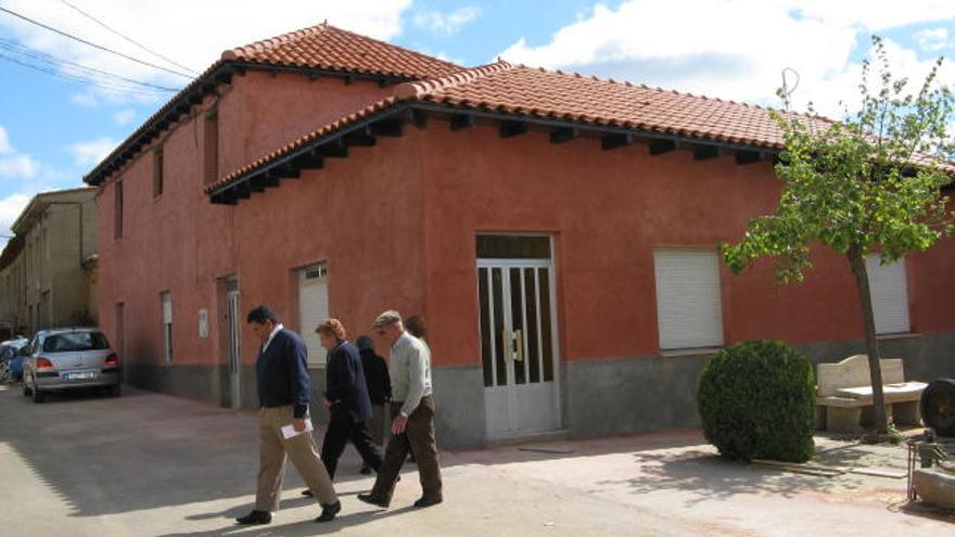 Varios vecinos pasan junto al edificio del antiguo Ayuntamiento de Bercianos, después de su remodelación