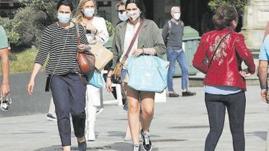 Gente paseando con mascarillas.