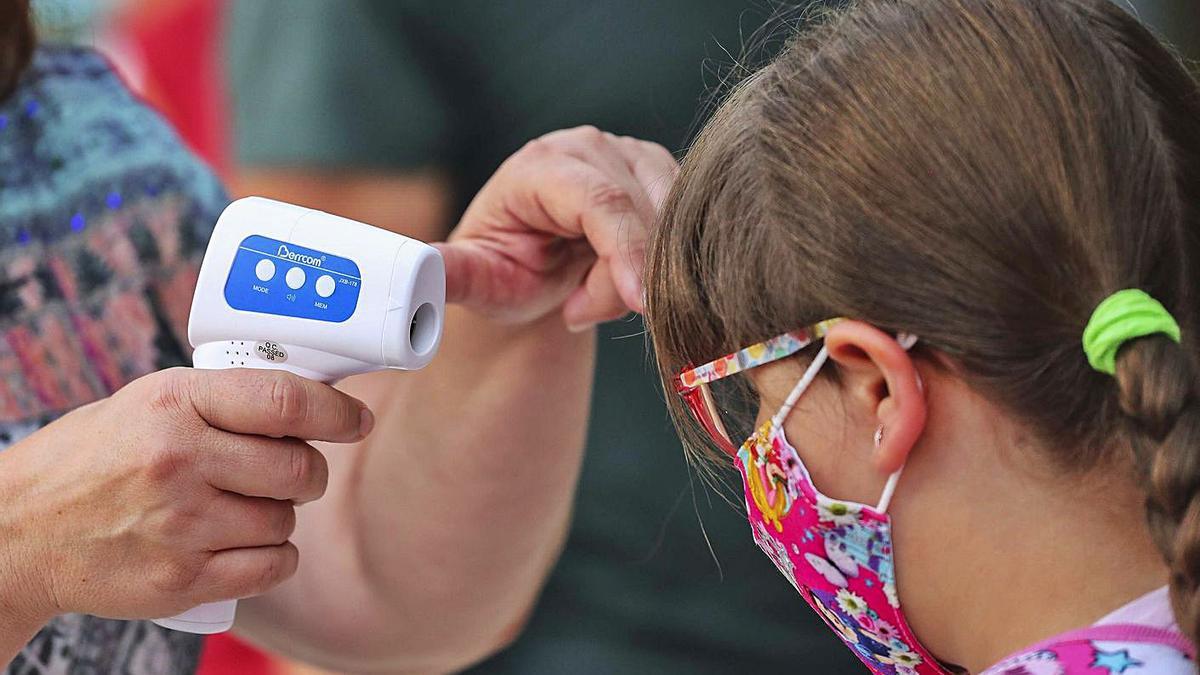 Una alumna con mascarilla, en el control de temperatura para acceder a su colegio. | FRANCISCO CALABUIG