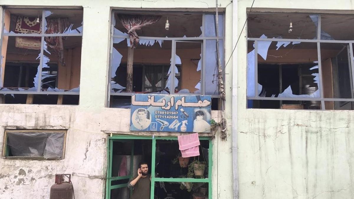 Un hombre habla por su teléfono móvil desde la entrada a su tienda dañada por un atentado cerca del Ministerio de Defensa en Kabul, Afganistán.