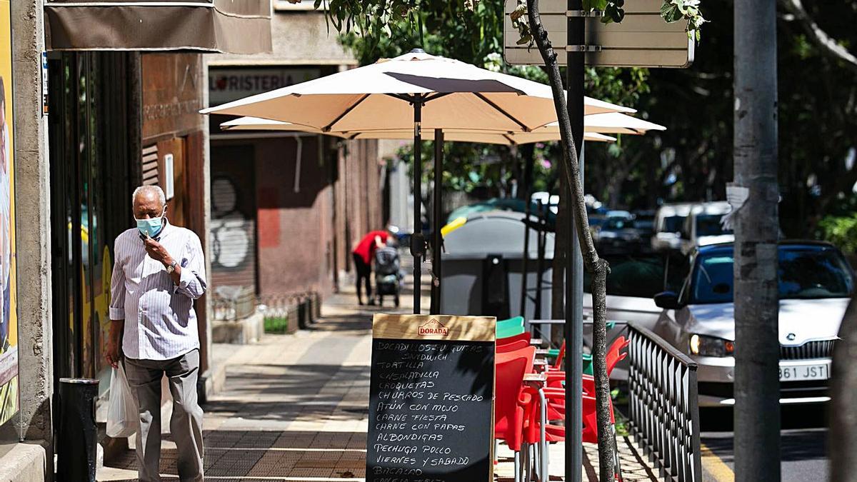 Un hombre camina por una calle en la que se ha instalado una terraza en Santa Cruz de Tenerife.