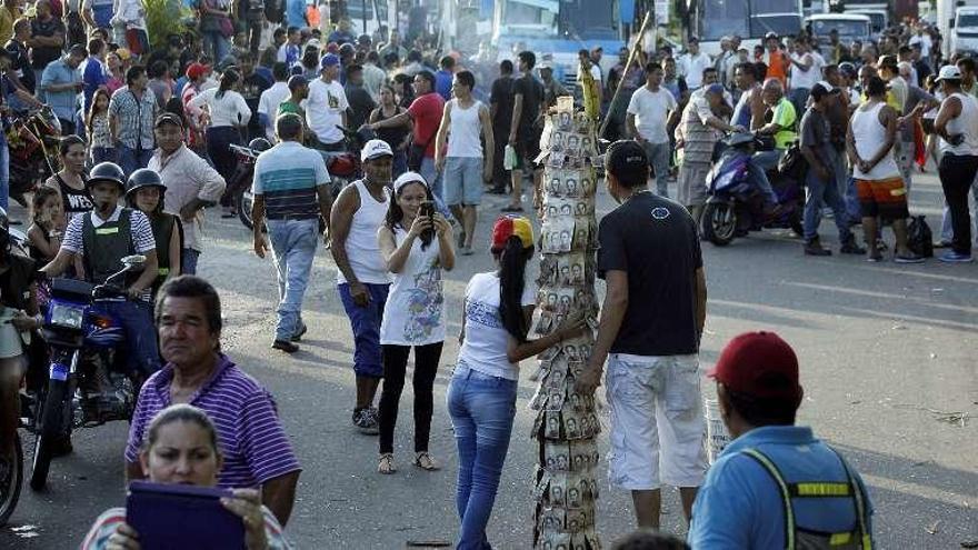 Venezolanos se fotografían ante un poste cubierto de billetes. // Reuters