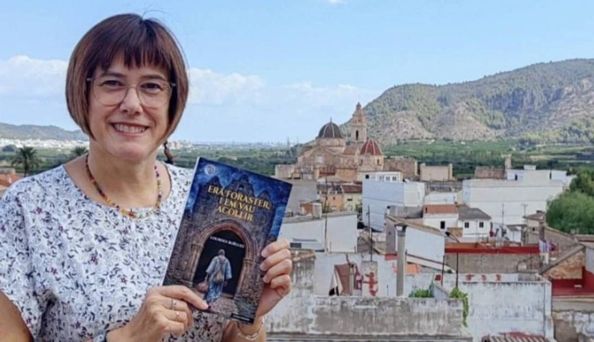La escritora, con uno de sus libros, ante la imagen de su Simat natal