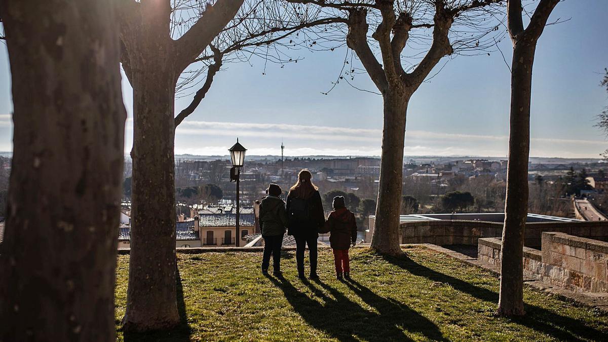 Una mujer junto a sus hijos, beneficiaria de Cáritas, contempla la ciudad. | Nico Rodríguez