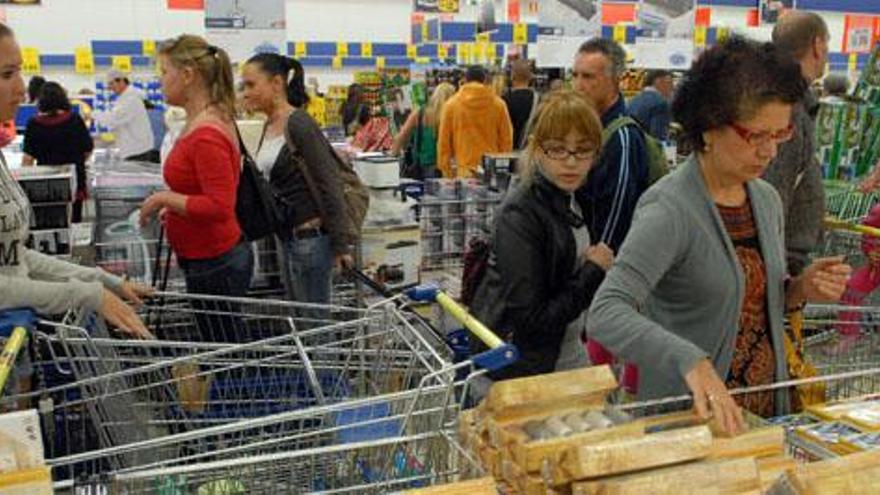 Arriba, varios clientes recorren los pasillos del supermercado Lidl de Maspalomas. Debajo, Cristian Mendoza y Zeneida Perdomo. i SANTI BLANCO