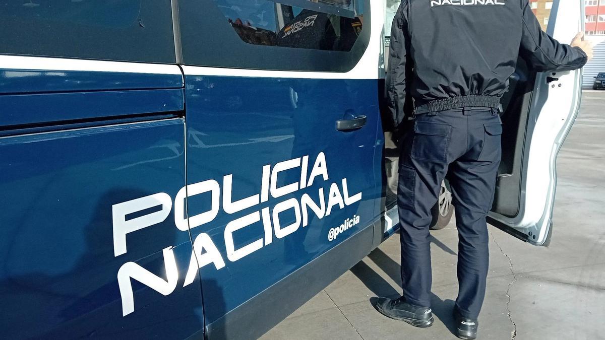 Un agente y un coche de la Policía Nacional.