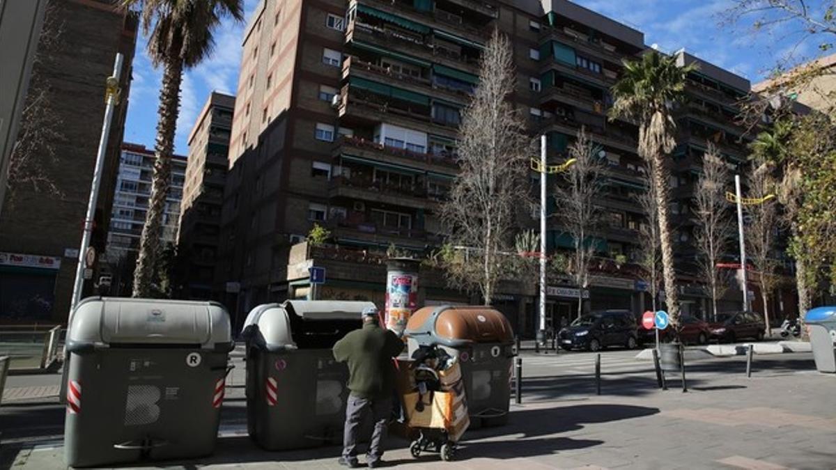 Un hombre escarba en un contenedor en la calle de Marne, en Nou Barris.