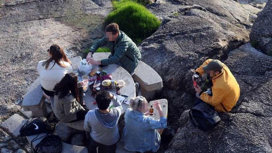 Jóvenes reunidos en una mesa en las rocas entre Orzán y Matadero, este lunes.