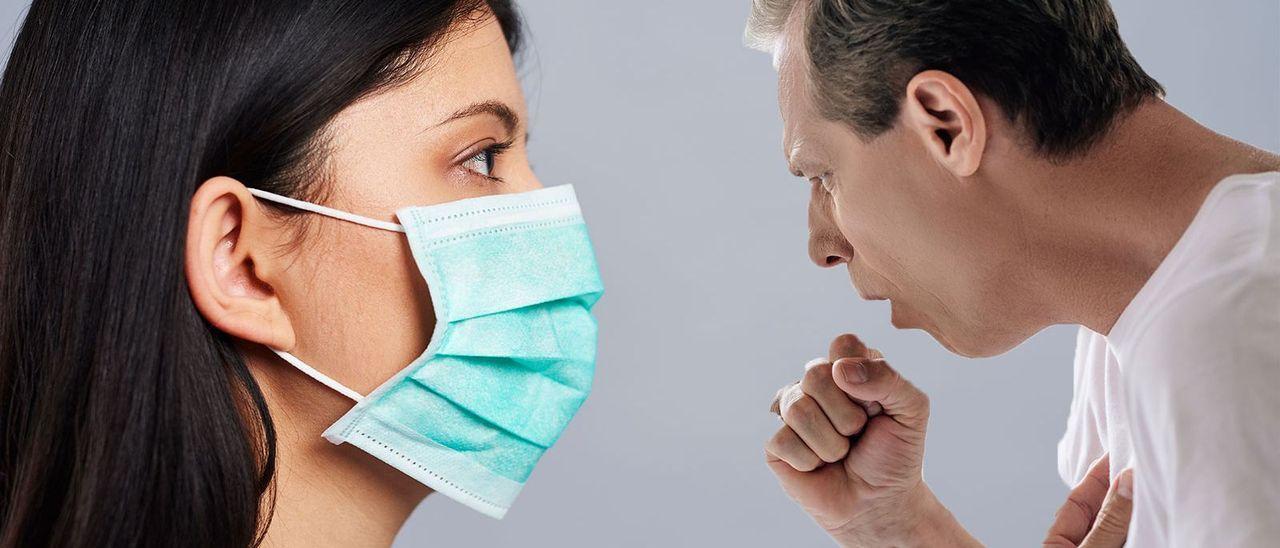 Una mujer con mascarilla frente a un hombre encamado con tos.