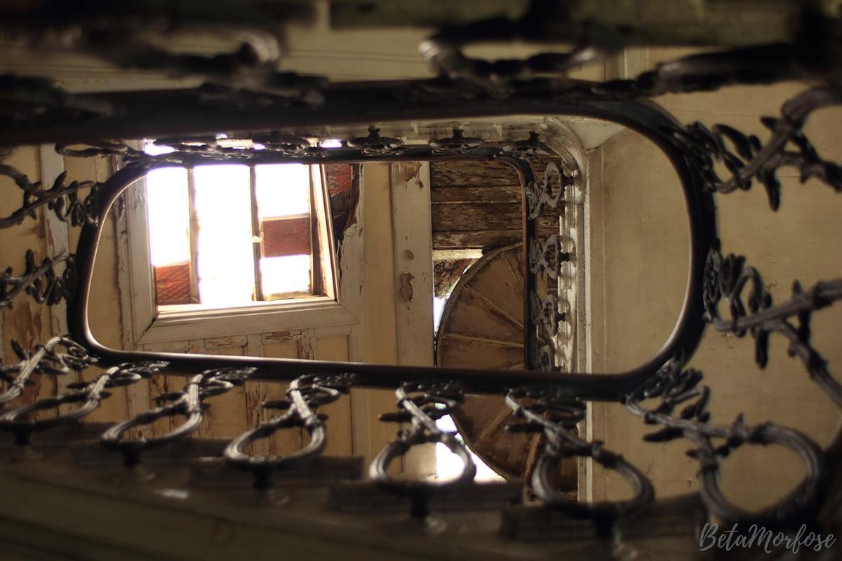 La escalera de forja, a través de la que se puede ver el techo derruído del edificio