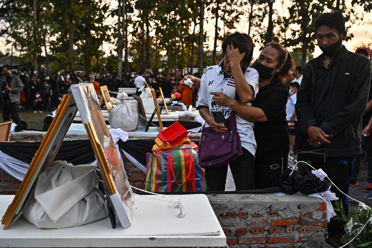 La gente observa cómo las piras funerarias incineran a 19 víctimas del tiroteo en la guardería de Uthai Suwan en el templo Wat Rat Samakee en Uthai Sawan. Un exoficial de policía disparó y mató a 37 personas, al menos 24 de ellos niños, después de irrumpir en una guardería infantil en el noreste de Tailandia.