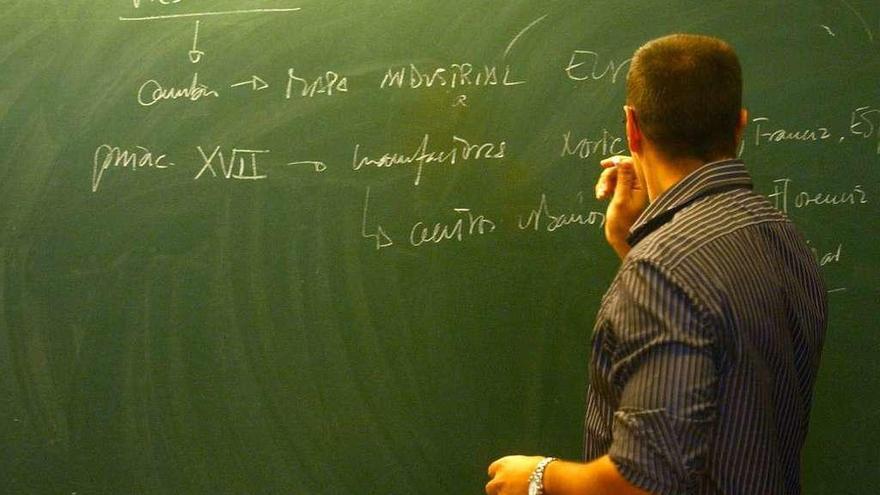 Un profesor gallego escribe en la pizarra durante una clase.