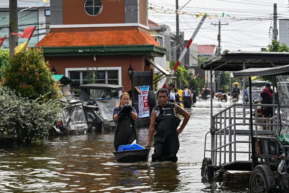 La gente camina a través de una calle inundada después de las fuertes lluvias traídas por el monzón del suroeste en Pampanga el 31 de agosto de 2026. (Foto de Jam STA ROSA / AFP)