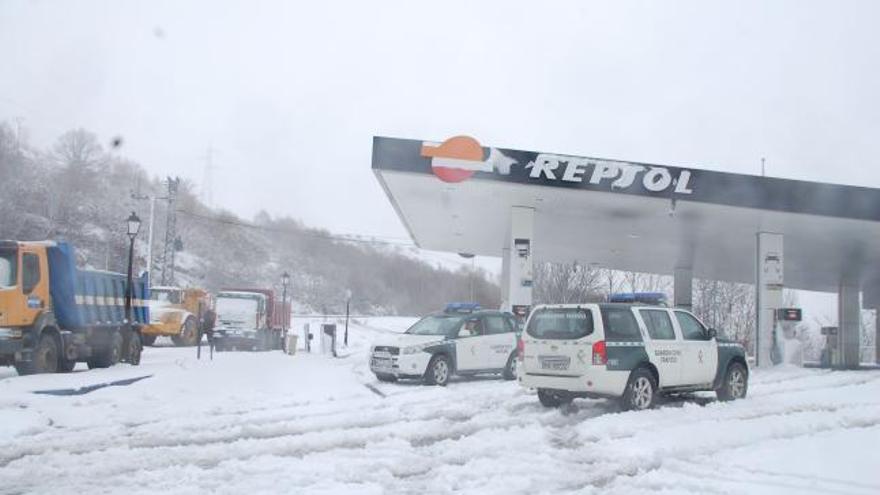 Dos coches de la Guardia Civil en una estación de servicio cubierta de nieve.