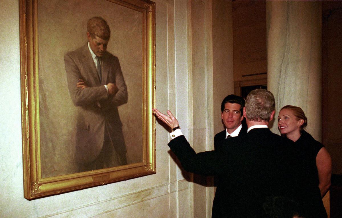 AP -BILL INGALLS-21/07/99-WASHINGTON- ARCHIVO--John F. Kennedy Jr. y su esposa Carolyn Bessette Kennedy hablan con el presidente Clinton en la Casa Blanca junto a un retrato del padre de Kennedy, el ex presidente John F. Kennedy, en esta fotografía de archivo del 5 de marzo de 1998. Los buzos de la Marina encontraron los cuerpos de John F. Kennedy Jr., su esposa y su cuñada entre los restos del avión de Kennedy, prácticamente poniendo fin a la dolorosa vigilia de cuatro días que soportaron sus familias durante la búsqueda en las aguas de Martha's Vineyard. El miércoles 21 de julio de 1999 se estaba realizando una inmersión para sacar los cuerpos a la superficie. (Foto AP/NASA, Bill Ingalls, archivo)