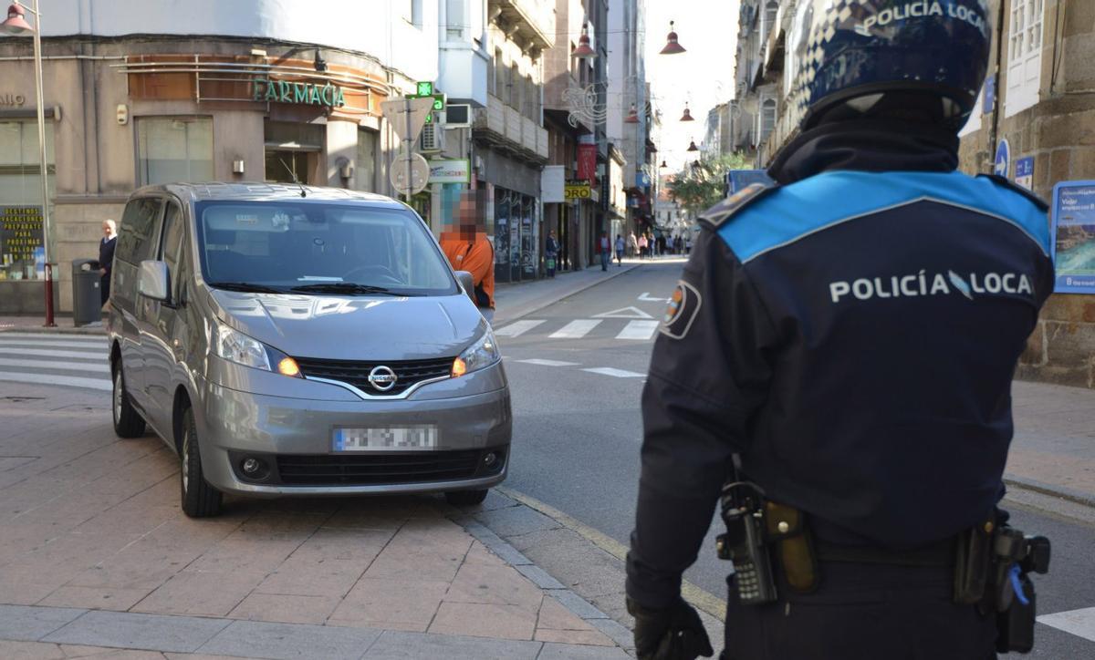 Un agente de la Policía Local, ante un coche estacionado encima de una acera.