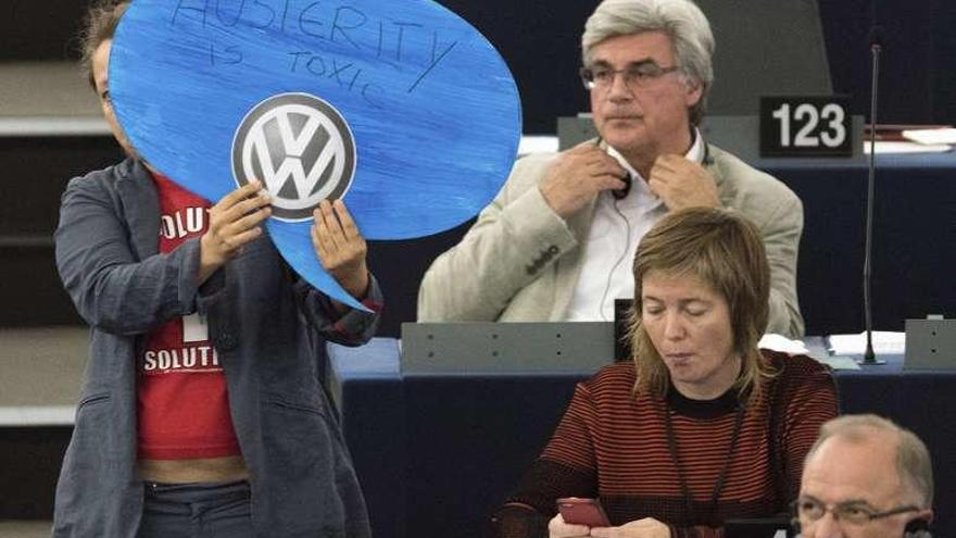 &quot;La austeridad es tóxica&quot;  |  El Dieselgate ha llegado al Parlamento Europeo en forma de protesta. Una europarlamentaria de izquierdas utilizó ayer el logo de Volkswagen para expresar su rechazo a las medidas de austeridad impuestas por países como Alemania para superar la crisis. En la foto, la europarlamentaria muestra el cartel durante la intervención de la canciller Angela Merkel, con el titular: &quot;La austeridad es tóxica&quot;.