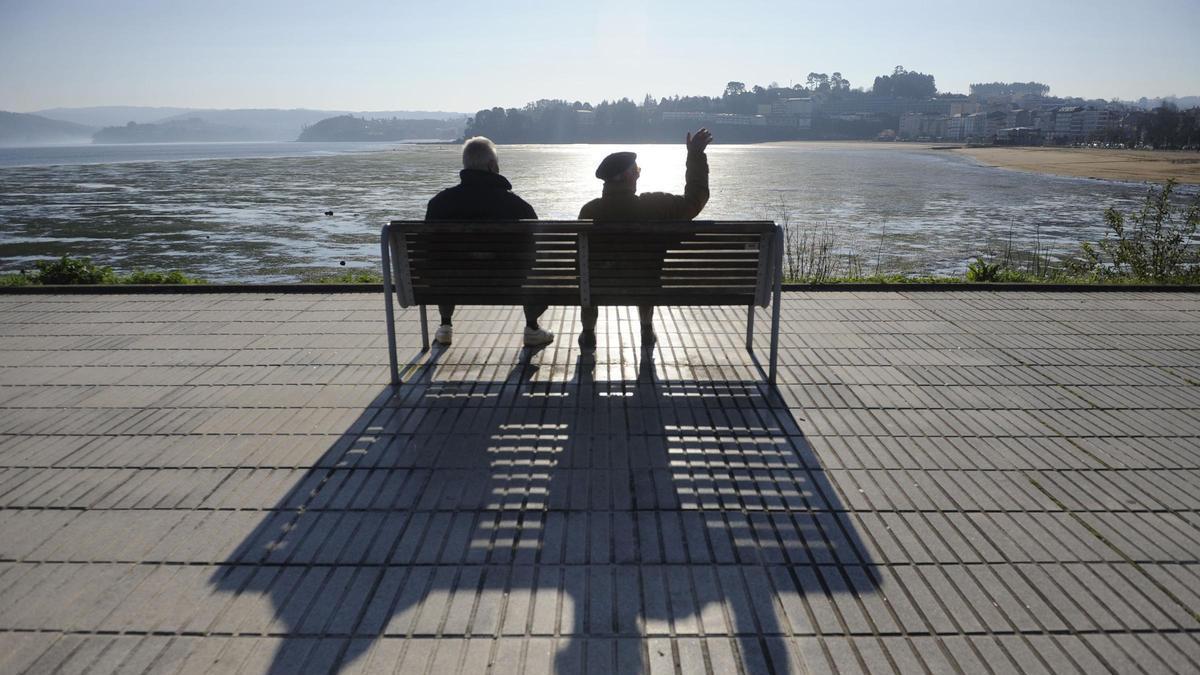 Dos jubilados descansan en un banco junto al mar.