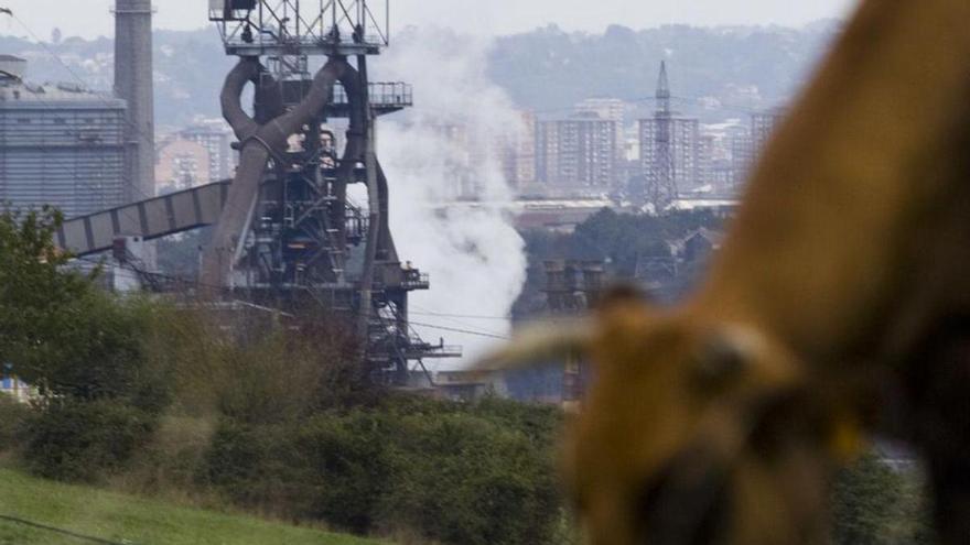 Una vaca pasta en un campo de Veriña, con la fábrica de ArcelorMittal al fondo. | JUAN PLAZA