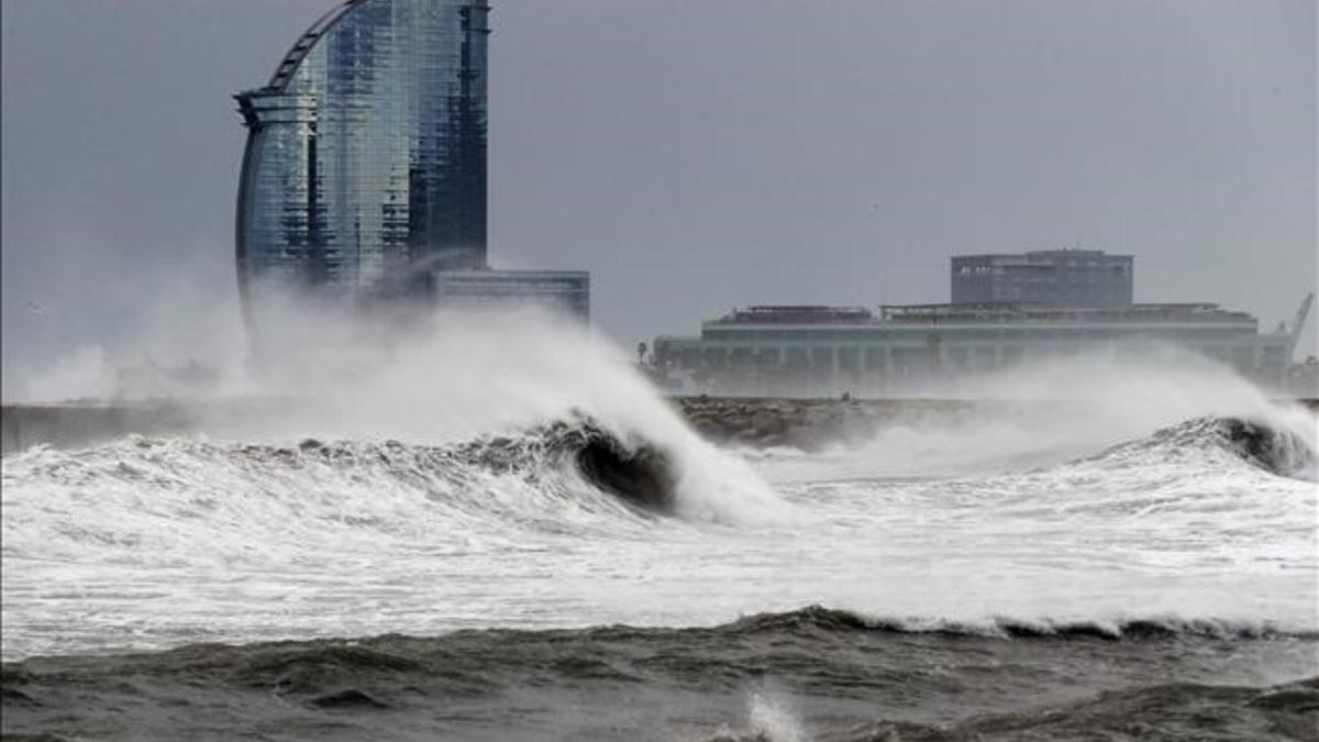 Olas en la playa de la Barceloneta con el hotel Vela al fondo.