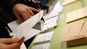 Un joven introduce la papeleta en el sobre para ejercer su derecho a votar.