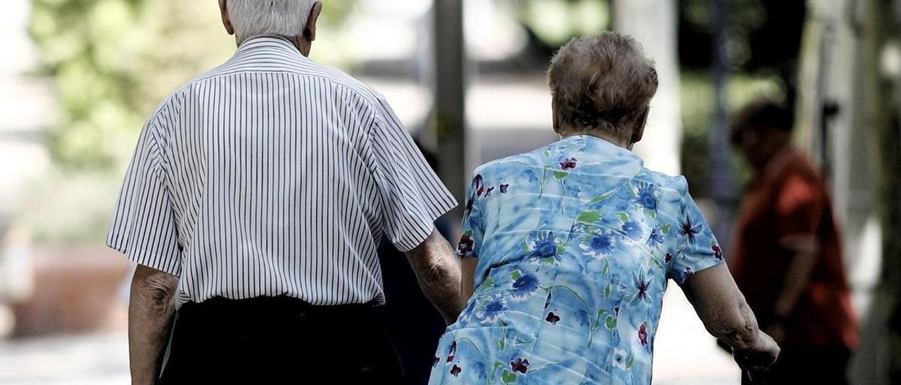 Una pareja de pensionistas pasea por un parque.