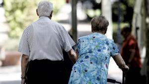 Una pareja de pensionistas pasea por un parque.