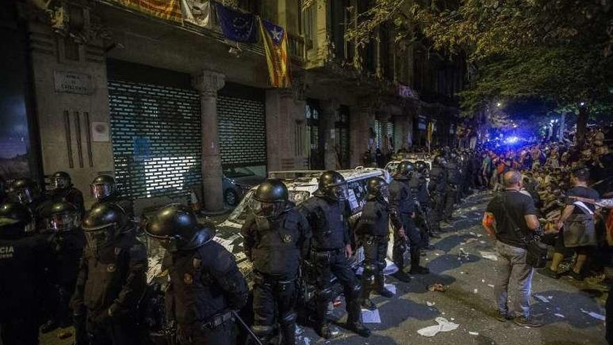 Despliegue de los mossos de madrugada ante la consejería de Economía; tras ellos las furgonetas de la Guardia Civil, que quedaron destrozadas..