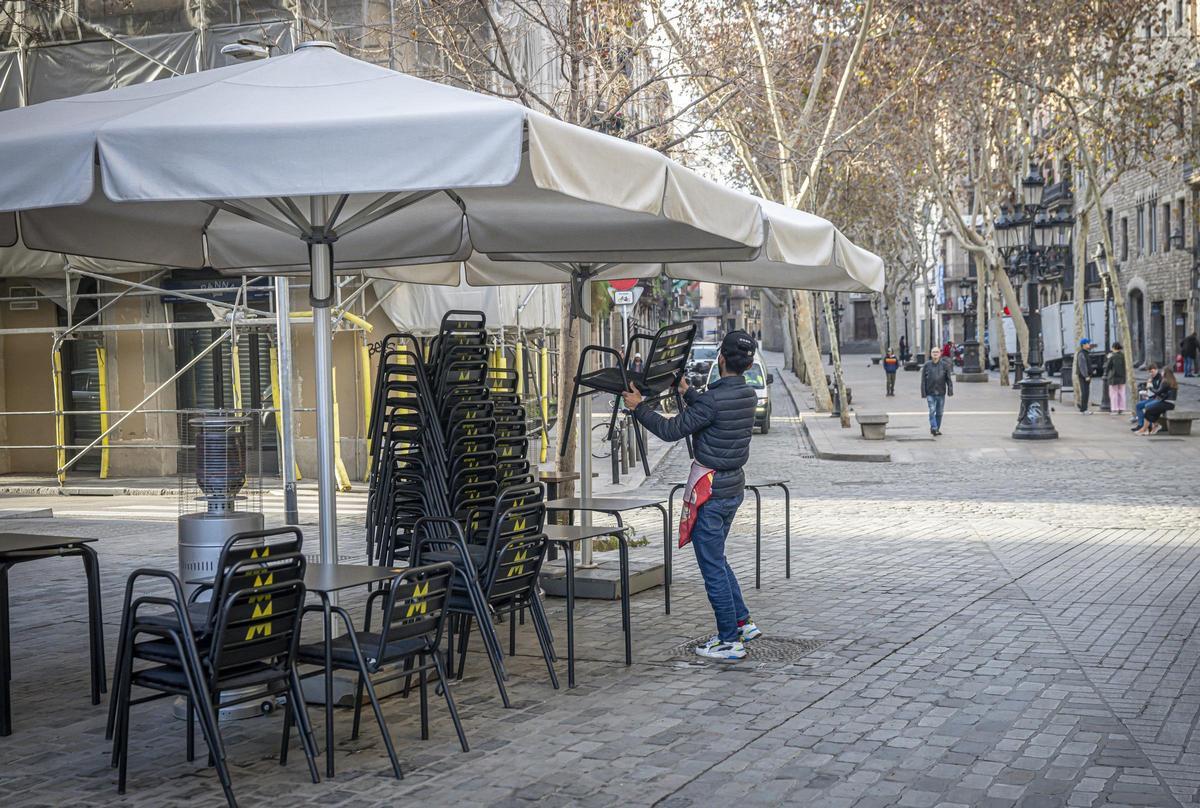 Un trabajador coloca las sillas y las mesas de una terraza en el paseo del Born, en Barcelona.
