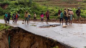 Un grupo de vecinos intenta arreglar los desperfectos ocasionados por el ciclón ’Batsirai en una carretera de Madagascar.