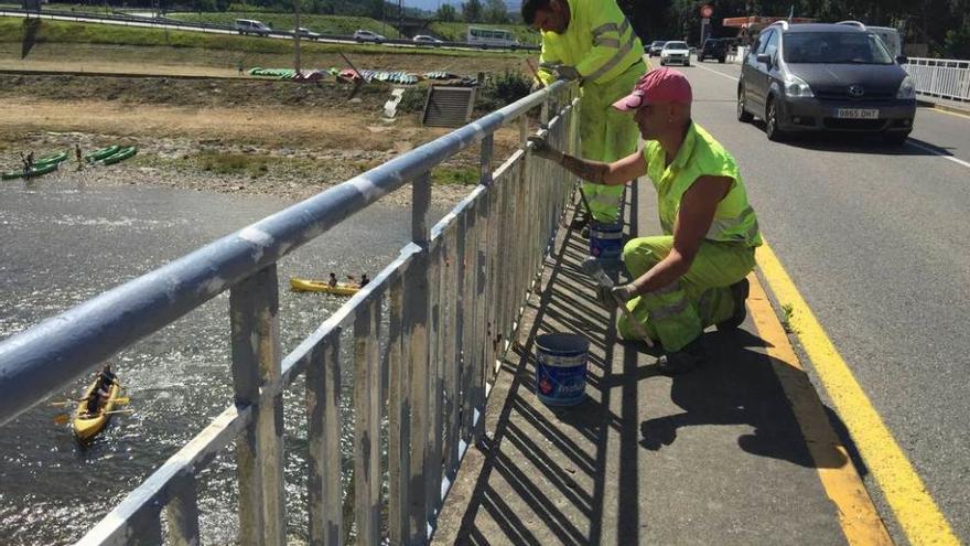 Operarios de la Demarcación de Carreteras pintan la barandilla del puente Emilio Llamedo de Arriondas, ayer.