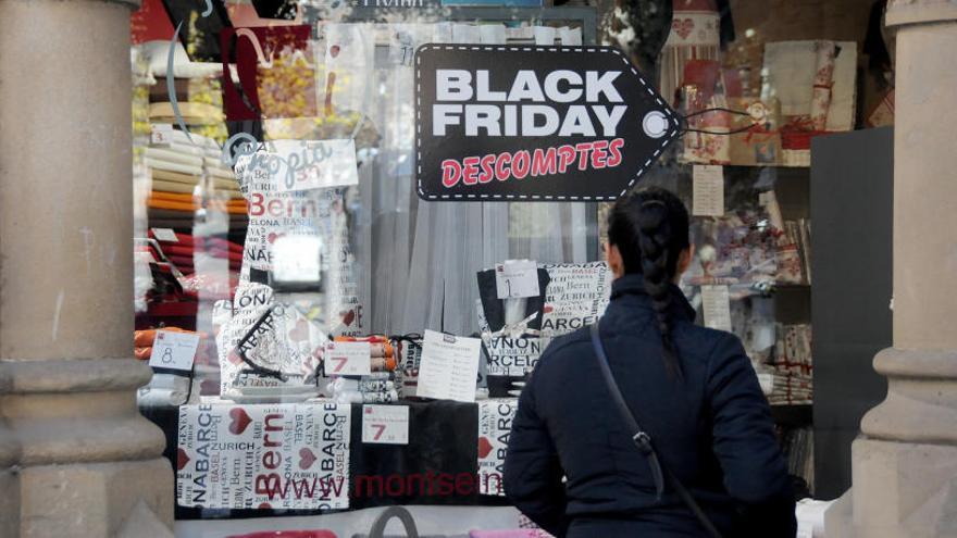 Compradors davant un cartell de descomptes pel Black Friday.